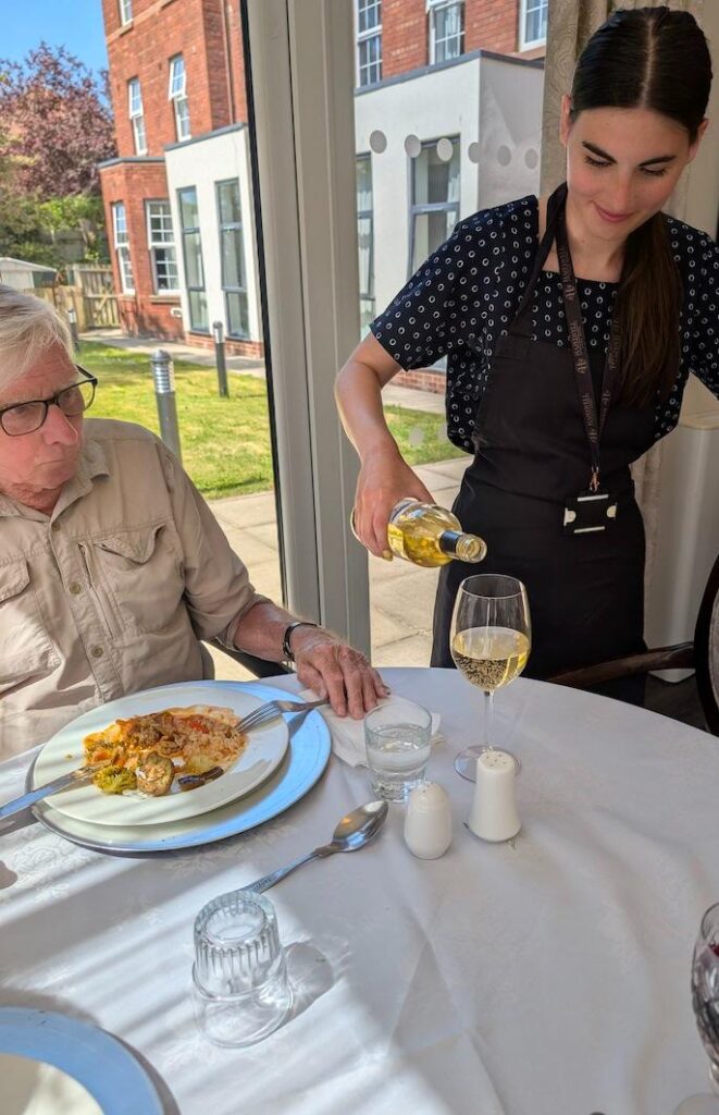 one of our team pouring wine for a resident