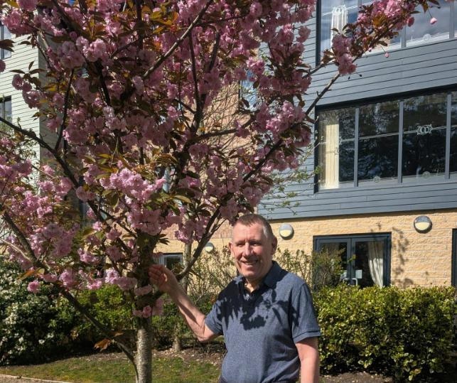 older man standing by a tree