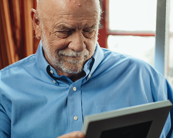An older man looking at a photo in a frame