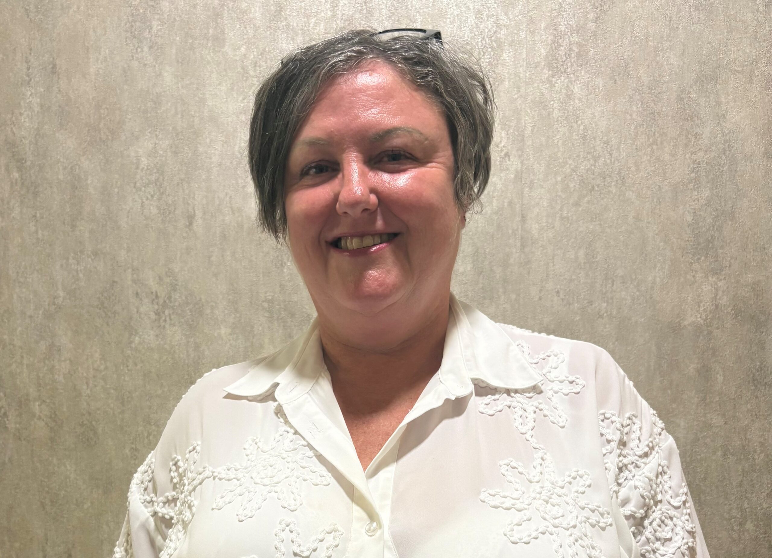 lady with short hair in a white top posing for staff photo