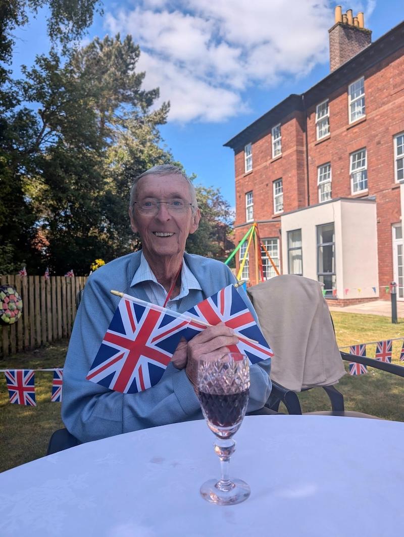 resident sat with flags in his hands smiling