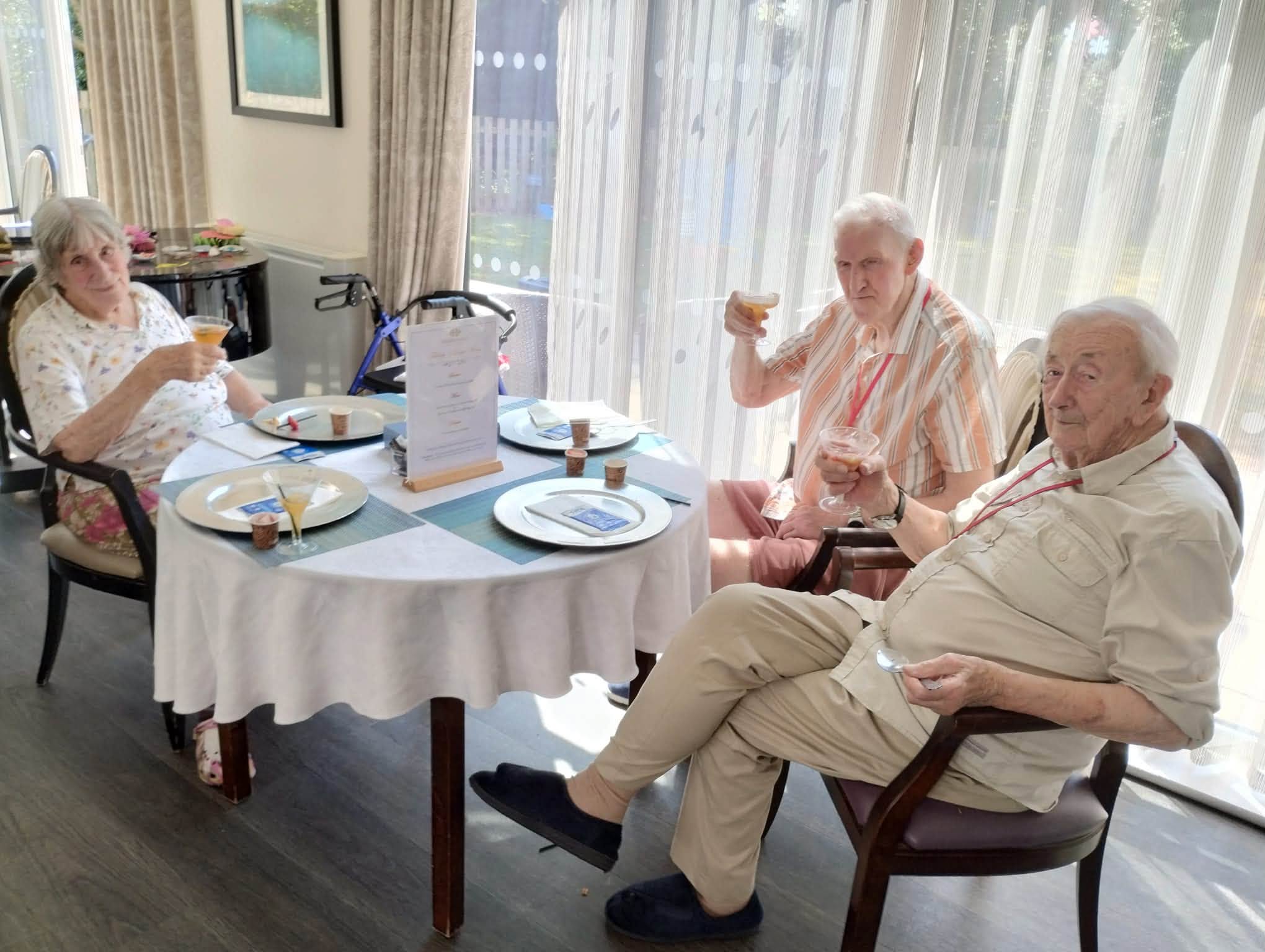 older adults sat at a table holding up glasses