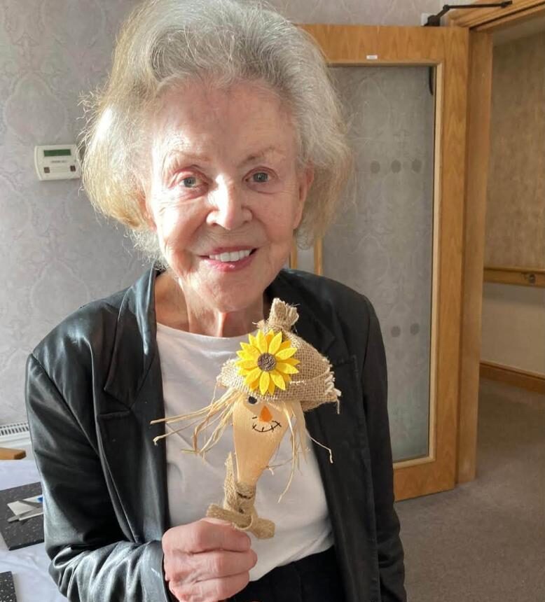 older lady holding a scarecrow
