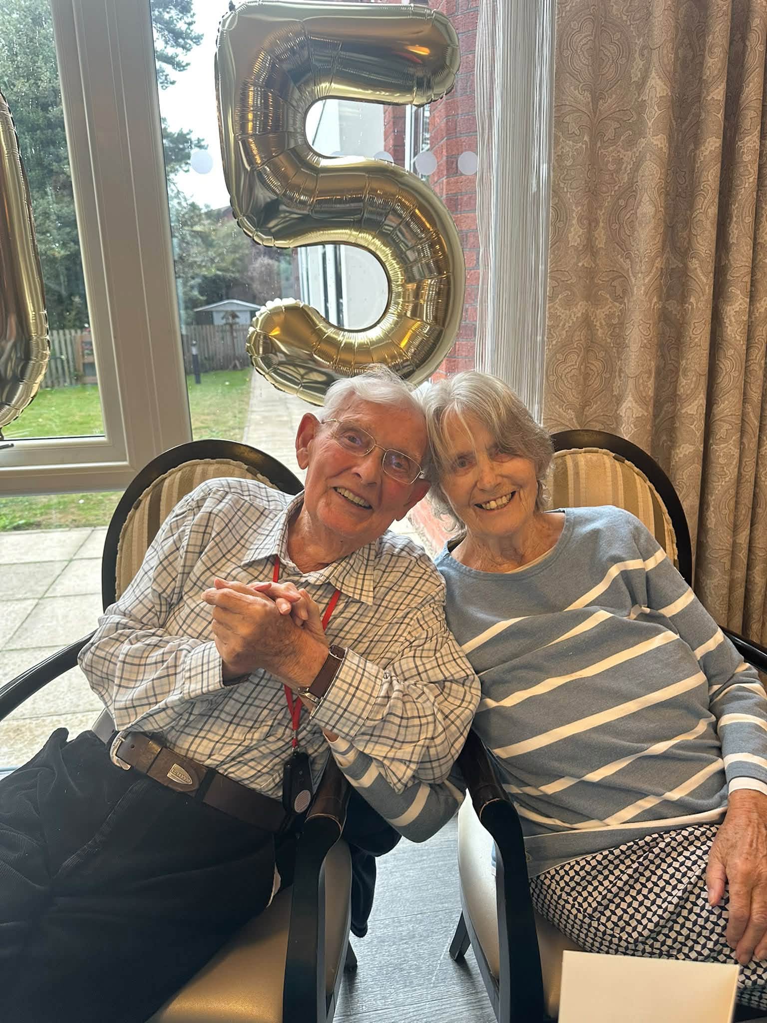 an older man and lady sat together smiling